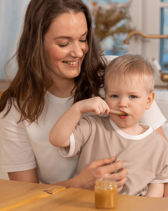 Mutter füttert Kleinkind mit einem Löffel